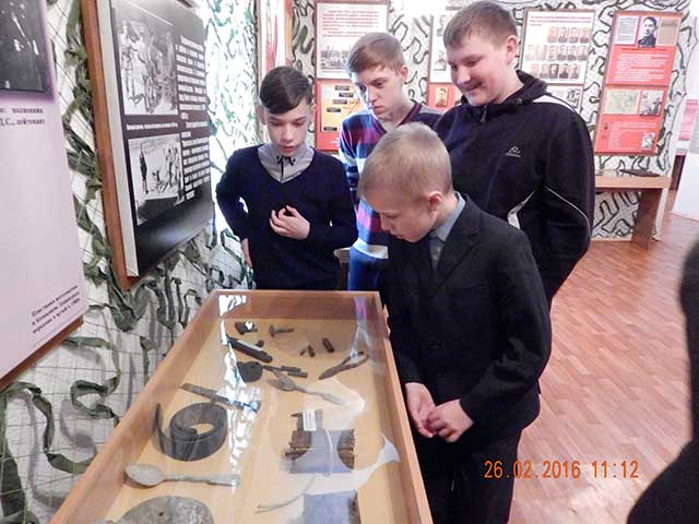 Экскурсанты рассматривают экспозицию музея, посвящённую ВОВ